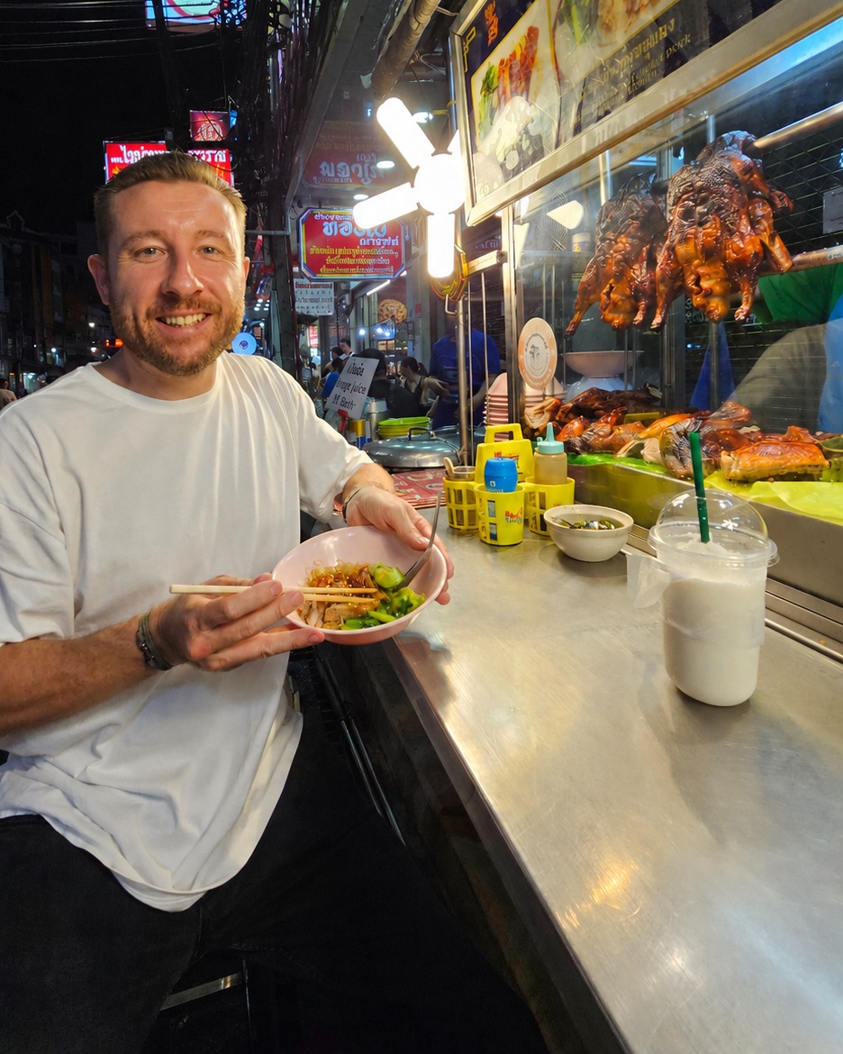 Jay, founder of WaveX Media, eating street food at a night market in Bangkok